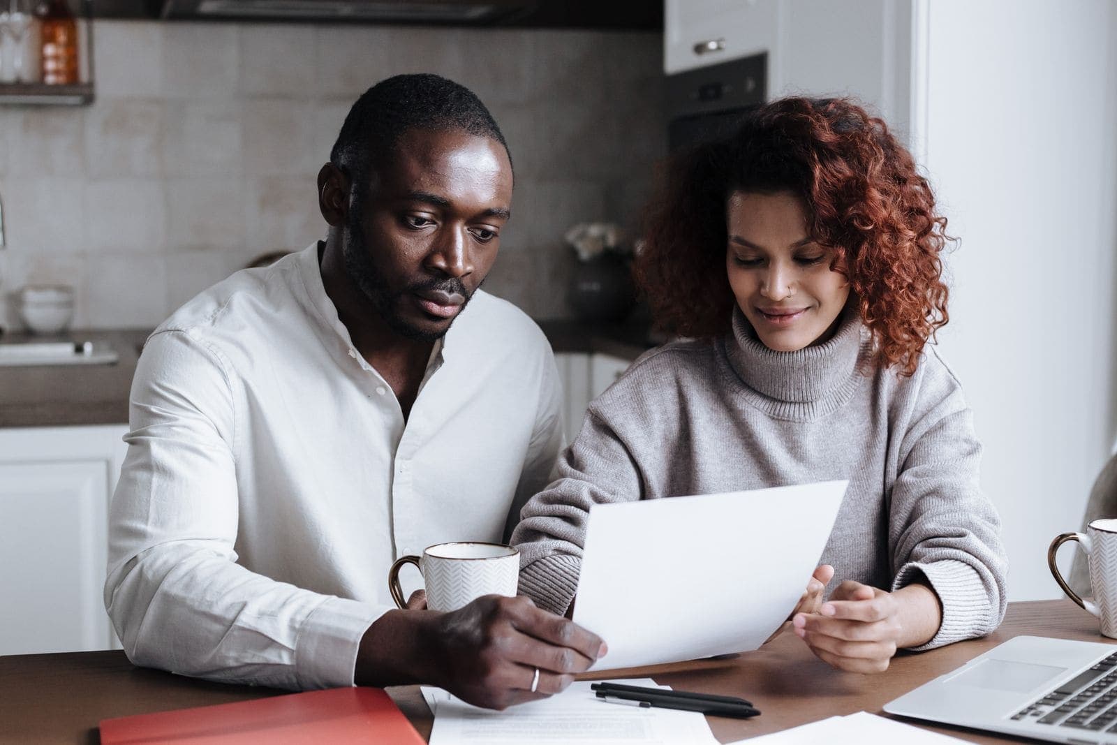 A couple reading through a letter together at the kitchen table