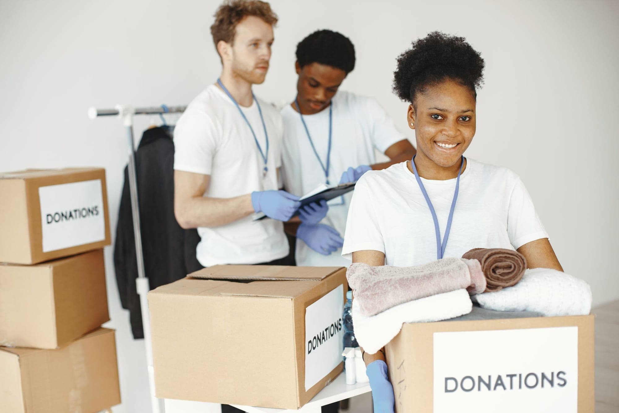 A smiling volunteer packing donation boxes with two fellow volunteers in a bright room