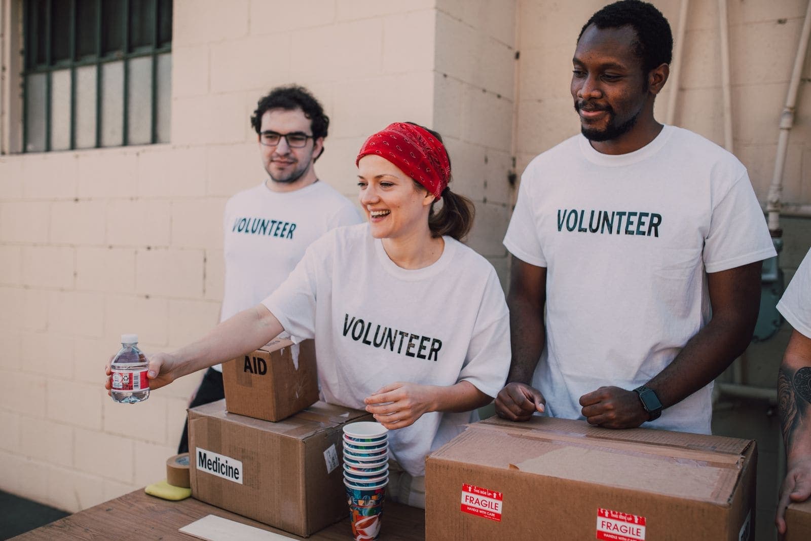 Smiling volunteers handing out bottled water and boxes of supplies